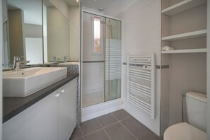A modern bathroom with a glass shower enclosure, a white sink, and a toilet. - 6 BEDROOM TOWNHOUSE TERRACE A6B002 (Cannes)