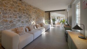 Un soggiorno moderno con una parete in pietra, un divano bianco e un tavolino in legno.
