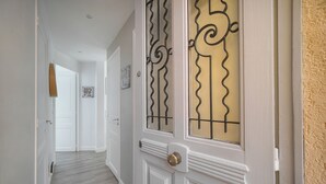 Un corridoio con una porta bianca decorata con barre metalliche e una maniglia in ottone.