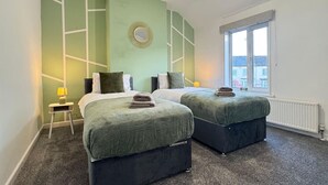 A hotel room with two beds, a window, and a radiator.