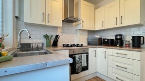 A modern kitchen with white cabinets, stainless steel appliances, and a wooden countertop.