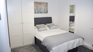 Une chambre à coucher avec un lit, une armoire et un tableau accroché au mur.