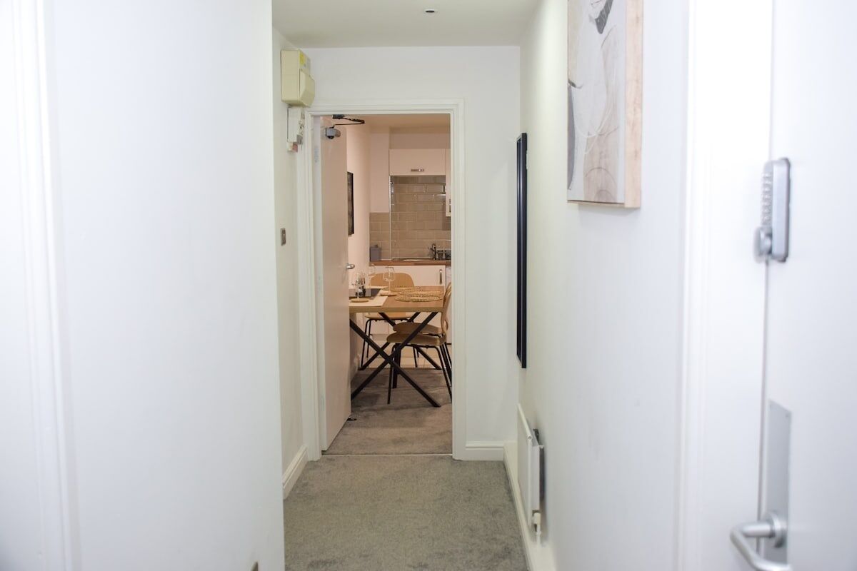 A narrow hallway leading to a kitchen with a dining table and chairs.
