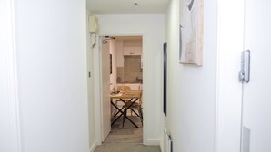 Un couloir étroit mène à une cuisine équipée d’une table et de chaises.