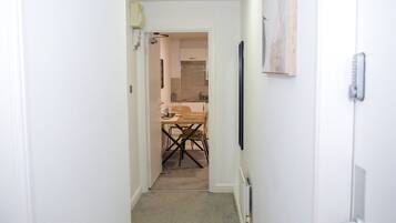 A narrow hallway leading to a kitchen with a dining table and chairs.