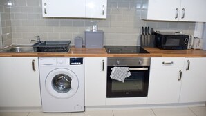 Une cuisine compacte équipée d’un lave-linge, d’un four, d’un four à micro-ondes et d’un grille-pain.