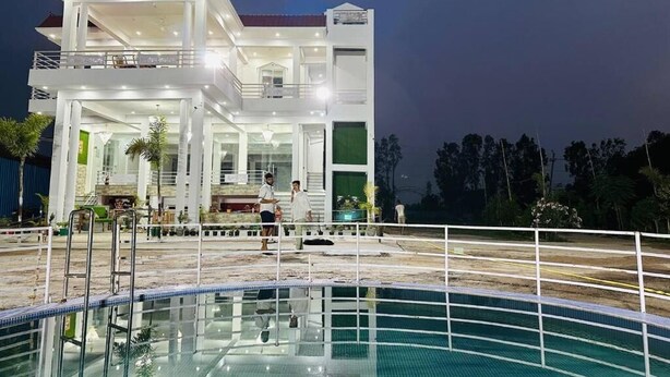 A modern hotel with a large swimming pool, multiple balconies, and a well-lit exterior. - R D Palace and Resort (Bakshi Ka Talab)