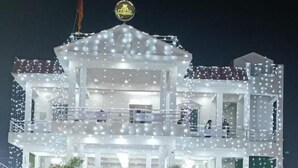 A multi-story building with a balcony, decorated with string lights and flags. - R D Palace and Resort (Bakshi Ka Talab)
