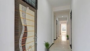 A hallway with a marble floor, a door with a unique design, and a potted plant. - R D Palace and Resort (Bakshi Ka Talab)
