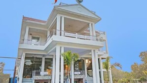 A two-story building with a balcony, a clock, and two flags on the roof. - R D Palace and Resort (Bakshi Ka Talab)