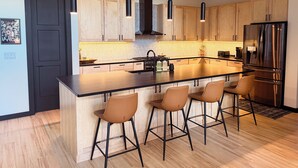 Una cucina moderna con una grande isola, mobili in legno, elettrodomestici in acciaio inossidabile e luci a sospensione.