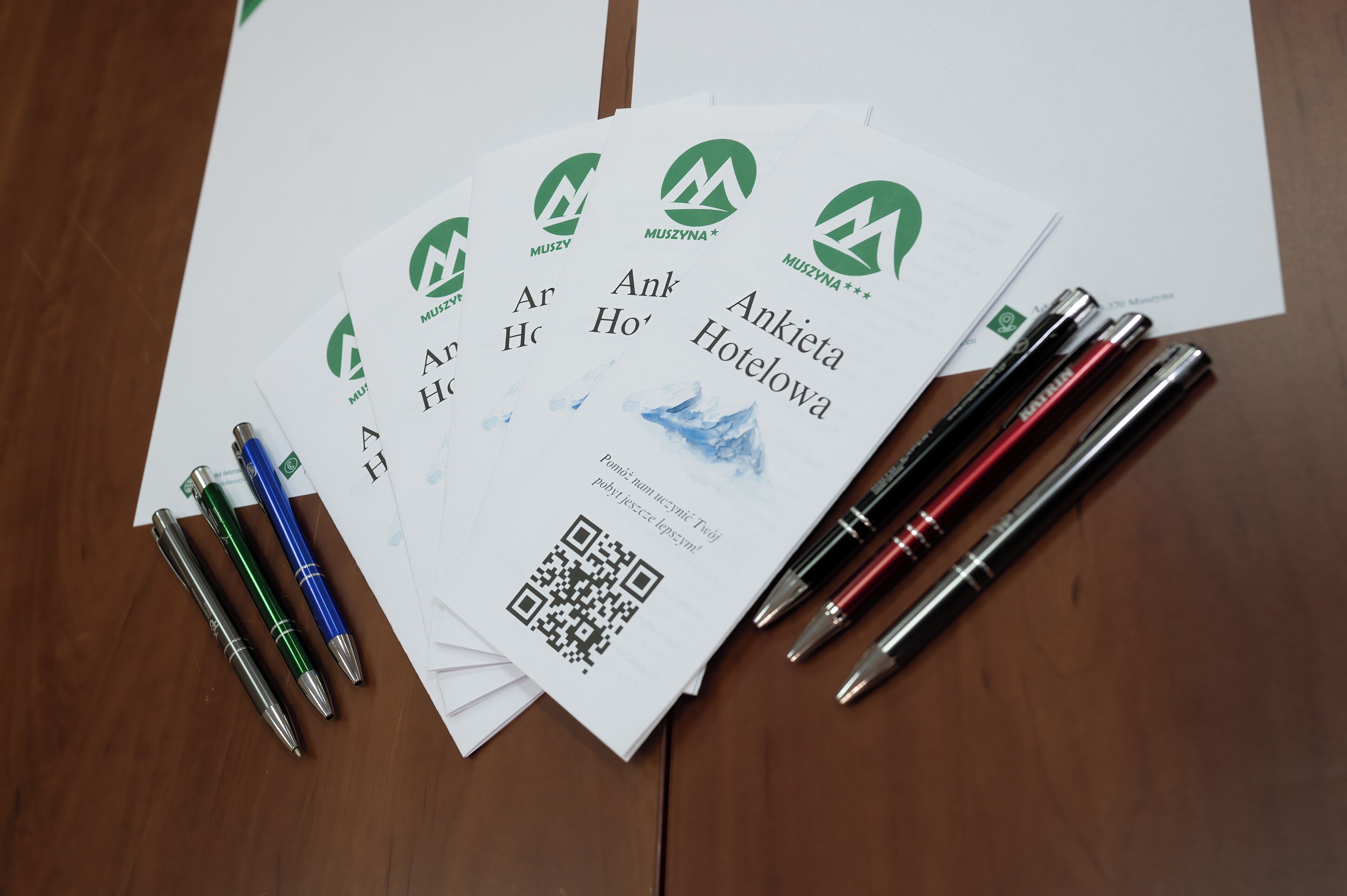 Una mesa con documentos impresos, bolígrafos y un código QR.