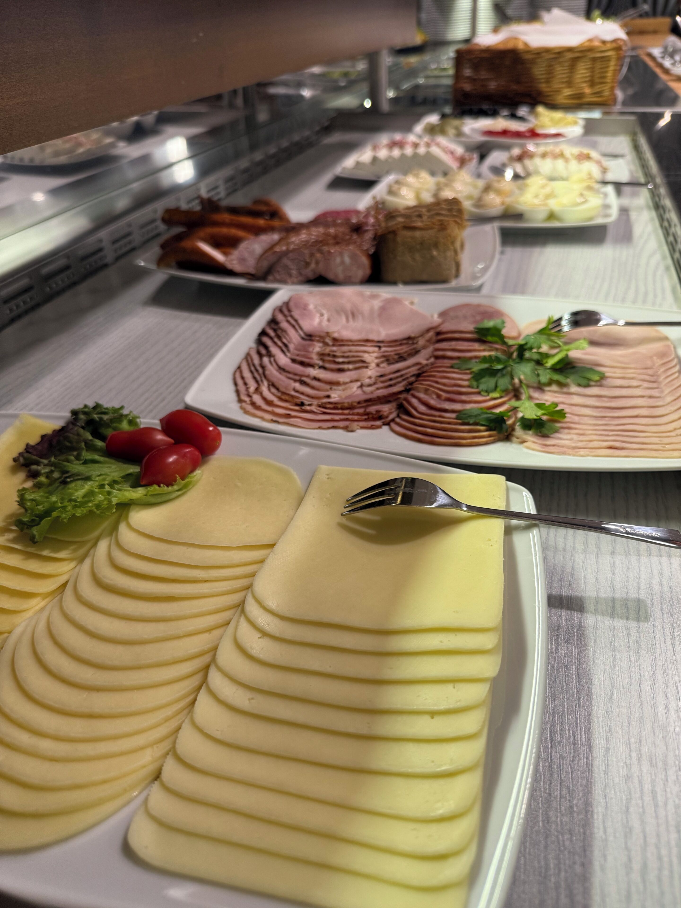 A buffet with various food items including sliced ham, cheese, and vegetables.