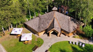 An aerial view of a lodge with a central building, a covered outdoor seating area, and a paved driveway.