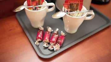 Two white cups with spoons, each containing a tea packet, on a tray with wrapped candies.