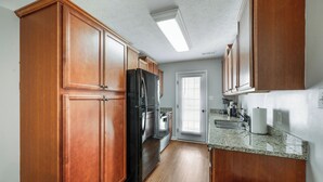 A kitchen with wooden cabinets, a black refrigerator, a granite countertop, and a window with blinds. - Luxury 3BR3BA 2 King Suites 5 Mins-Liberty University Family Friendly Townhouse (lynchburg)