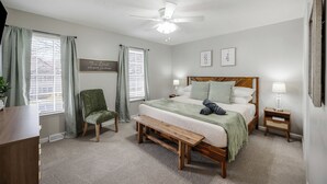 A bedroom with a bed, a chair, a bench, a nightstand, a ceiling fan, and a window with curtains. - Luxury 3BR3BA 2 King Suites 5 Mins-Liberty University Family Friendly Townhouse (lynchburg)