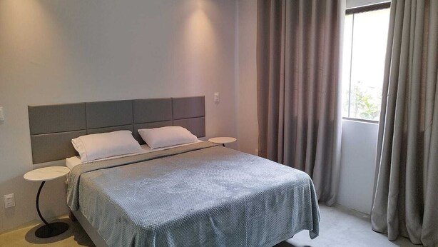 A modern bedroom with a large bed, two bedside tables, and a window with curtains. - Modern house in Serra do Cipó, a peaceful place in an excellent location. (Serra do Cipó)