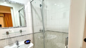 A bathroom with a glass-enclosed shower, a white sink, and a mirror above the sink. - HS Altet Suites - Alicante Airport (Elche)