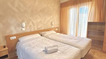 Een hotelkamer met twee bedden, een houten hoofdeinde, een hangende lamp en een inbouwkast.