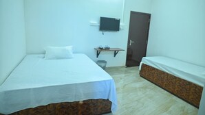 A room with a bed, a television mounted on the wall, a door, and a small table. - Hotel Tricon Residency (Guwahati)