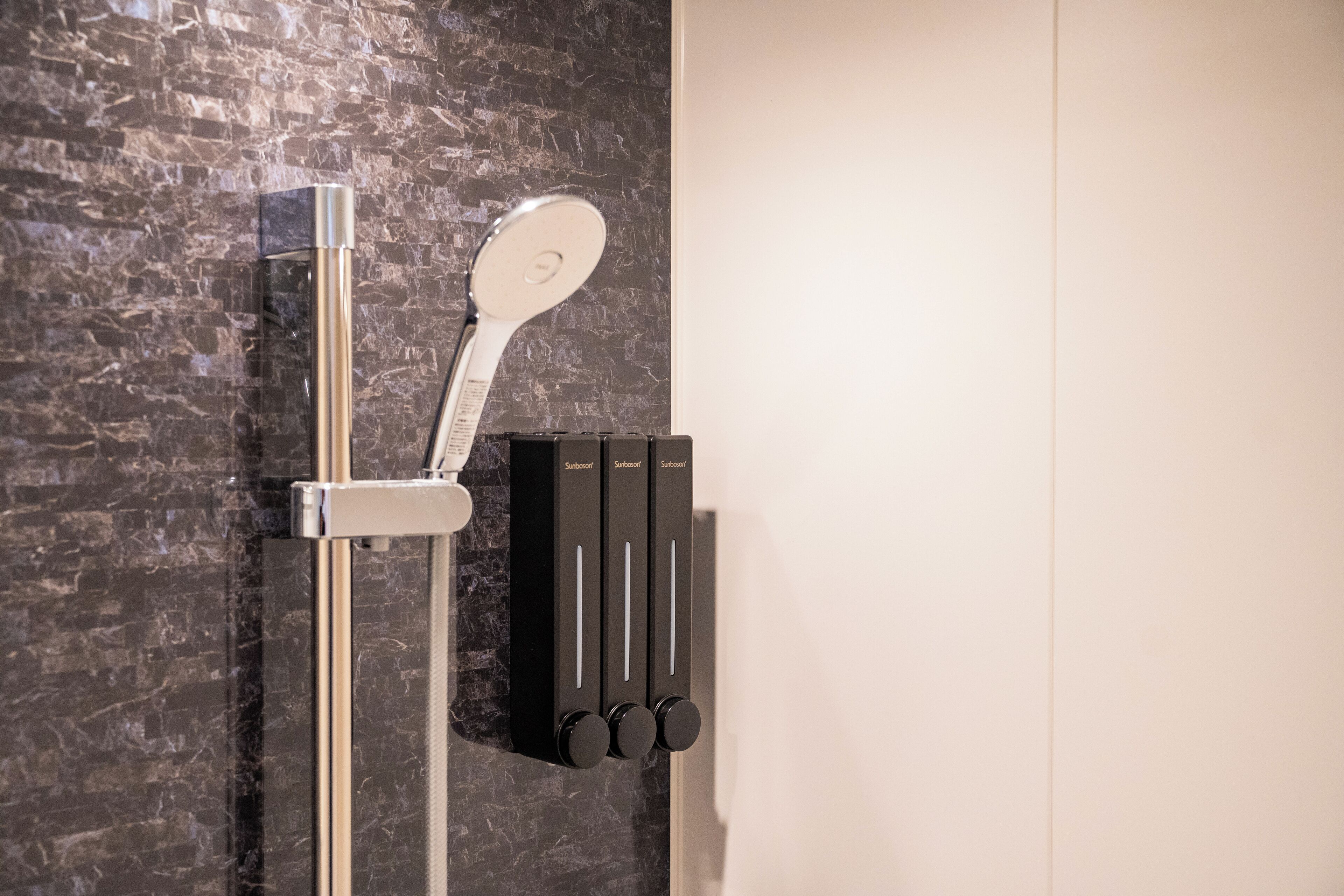 A modern shower with a handheld showerhead and a wall-mounted control panel.