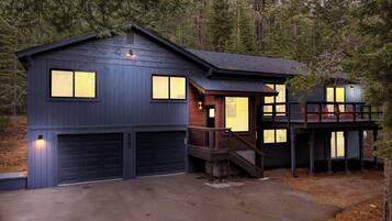 A two-story house with a garage, a deck, and a staircase leading to the upper level.