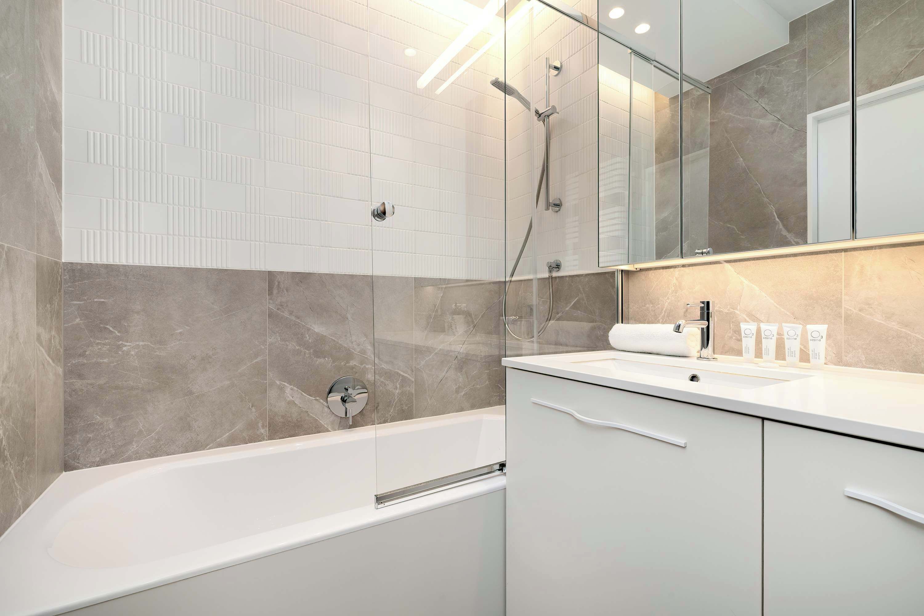 A modern bathroom with a bathtub, a glass shower enclosure, and a vanity with a sink.