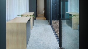 Un interior moderno con techo de madera, un largo pasillo, una recepción y una pared de vidrio con vistas.