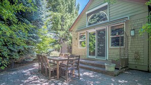 A patio with a table and chairs, a house with a window, and a brick wall. - Cozy Ketchum Retreat - A Highly Sought-After, Pet-Friendly Getaway (Ketchum)
