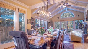 A dining area with a wooden table set for four, surrounded by chairs, with a large window and a ceiling fan above. - Cozy Ketchum Retreat - A Highly Sought-After, Pet-Friendly Getaway (Ketchum)