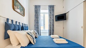 A hotel room with a bed, a TV mounted on the wall, and a window with curtains. - Ammore A Mare - Luxury Apartment Near The Sea (Napoli)