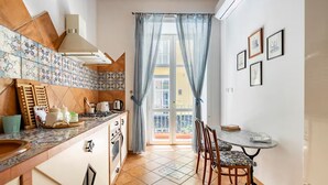 A compact kitchen with a dining area, featuring a tiled backsplash, wooden cabinets, and a view to the outside. - Ammore A Mare - Luxury Apartment Near The Sea (Napoli)