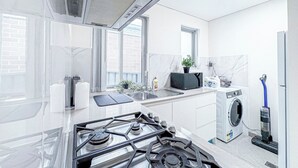 A modern kitchen with a gas stove, sink, and a built-in washing machine. - 1BR Granny Flat / Free Parking / Near Airport & Train (Arncliffe)