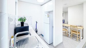A compact kitchen with white cabinets, a built-in sink, and a small dining area with a wooden table and chairs. - 1BR Granny Flat / Free Parking / Near Airport & Train (Arncliffe)