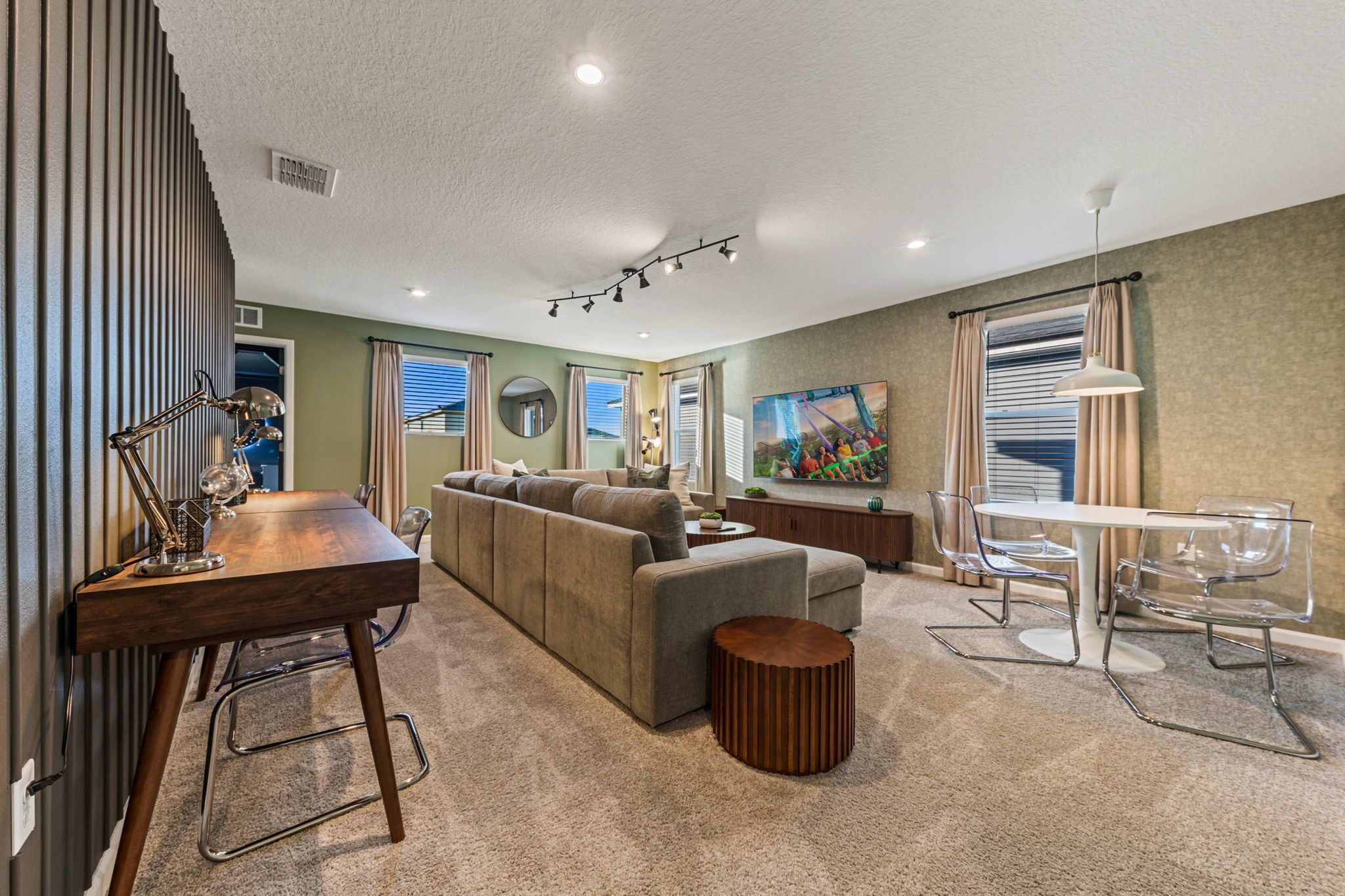 A modern living room with a sofa, a dining table, and clear chairs.