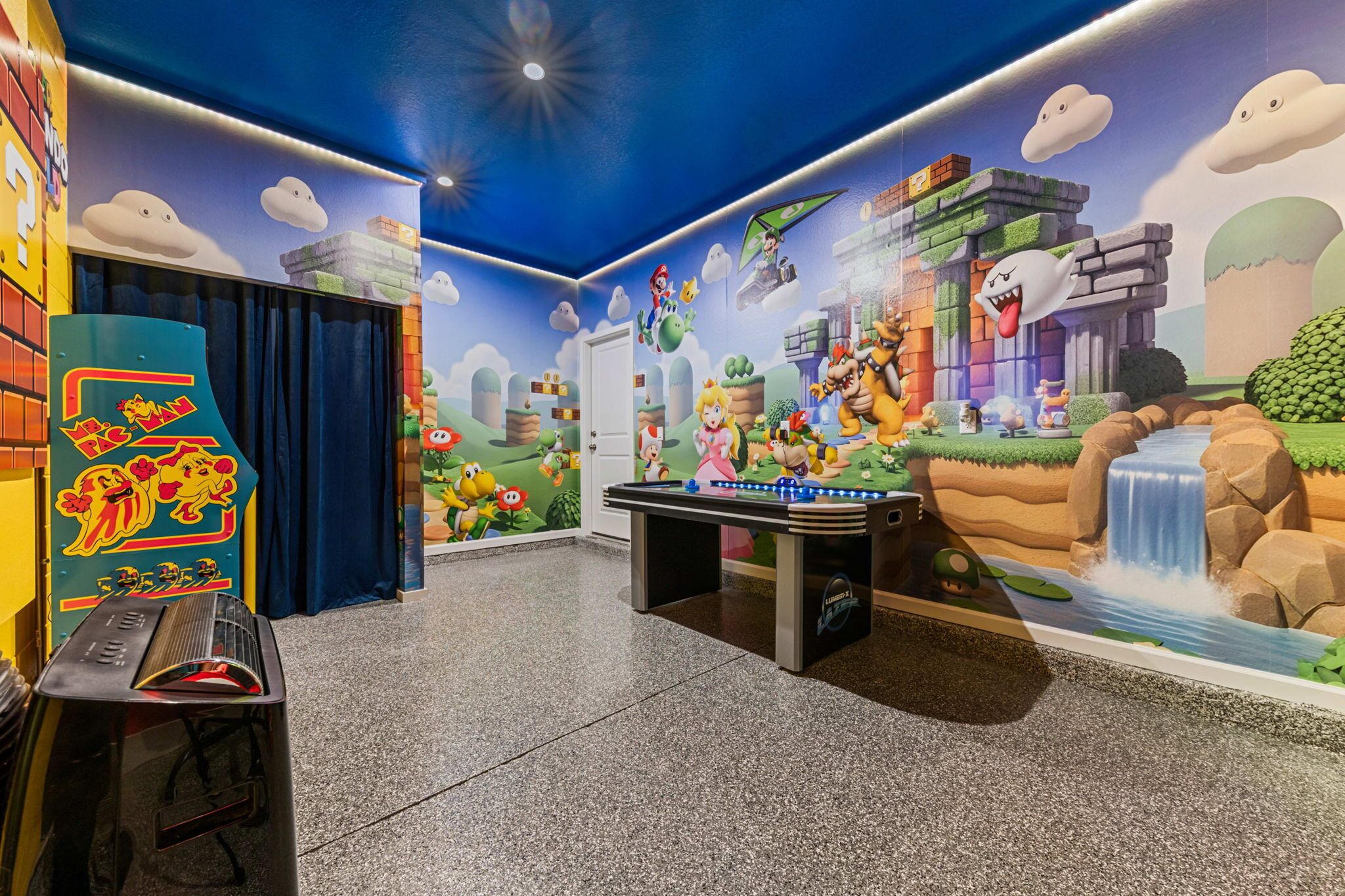 Une pièce équipée d’un baby-foot, d’une table de billard et ornée d’une fresque représentant des personnages de jeux vidéo.