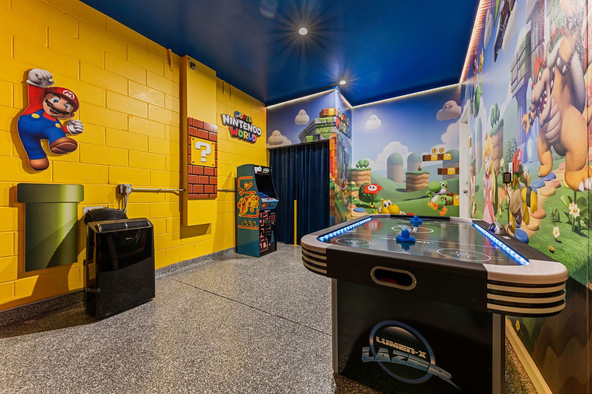 Un espace de jeux avec un mur décoré sur le thème de Mario, une table de baby-foot et un panneau « Nintendo World ».