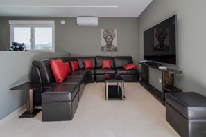 A modern living room with a sectional sofa, red cushions, a small coffee table, a TV, and artwork on the walls.