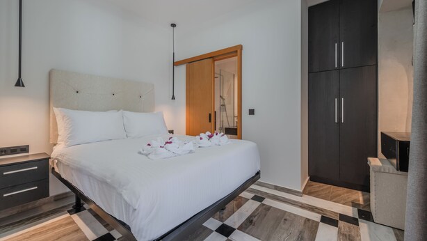 Un dormitorio moderno con cama, mesitas de noche, un armario y zona de ducha.