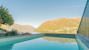 A swimming pool with a clear view of mountains and a town in the background. - Villa Regina Retreat With Pool & Lake View (Brienno)