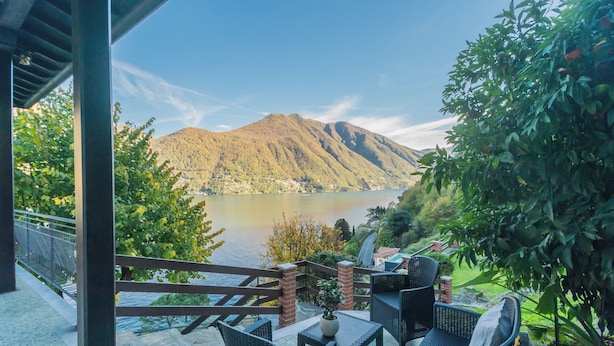 A terrace with outdoor seating, a view of a lake, and mountains in the background. - Villa Regina Retreat With Pool & Lake View (Brienno)
