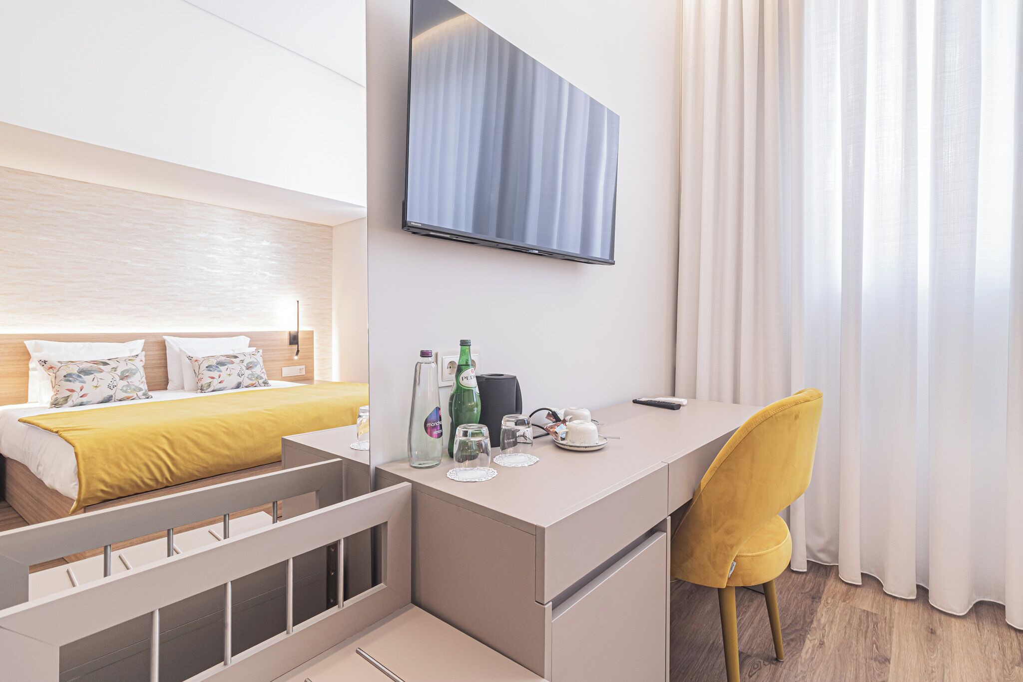 A modern hotel room with a bed, a desk, and a TV.