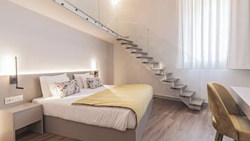 Quarto moderno com cama, mesa de cabeceira e escada que leva a um andar superior.