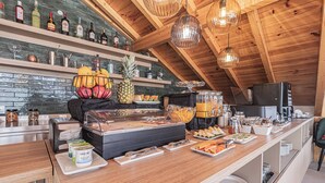 A breakfast buffet with various food items, a coffee machine, and a wine rack. - Galega Villas (Mafra)