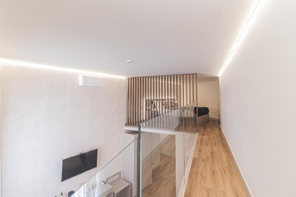Un interior moderno con barandilla de vidrio, suelo de madera y diseño minimalista.