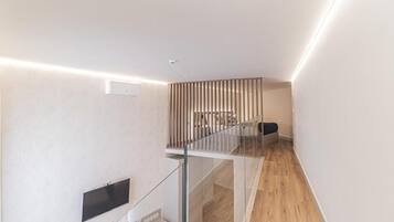 Un interior moderno con barandilla de vidrio, suelo de madera y diseño minimalista.