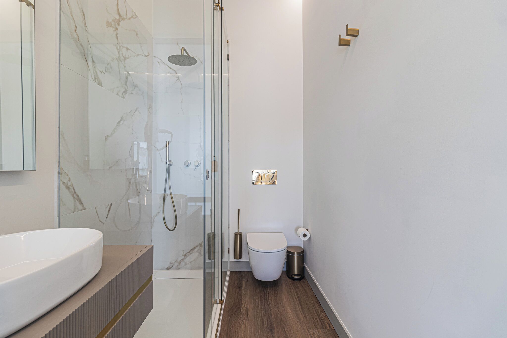 Un baño moderno con ducha envuelta en vidrio, inodoro blanco y una bañera grande de color blanco.