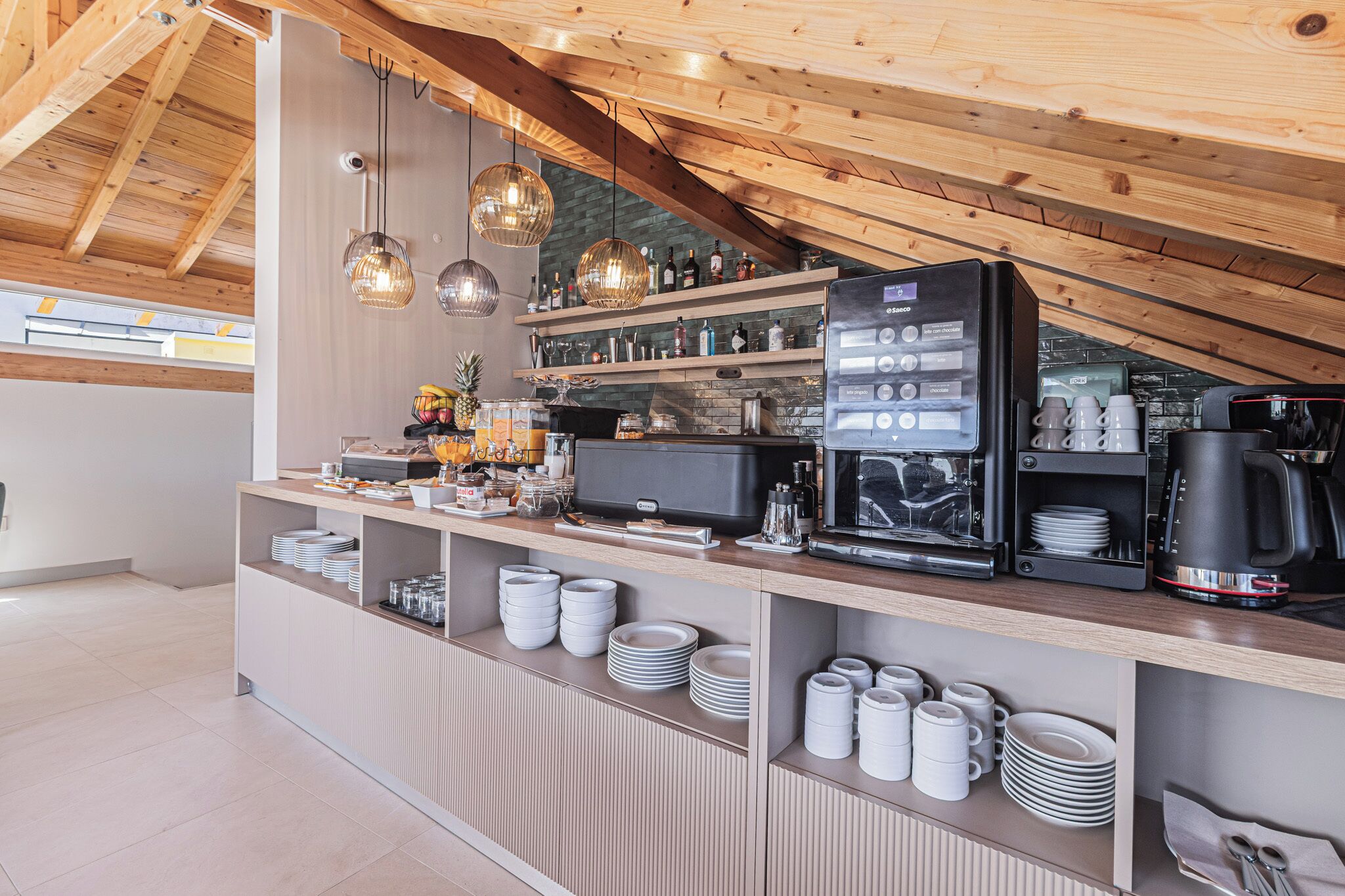 Un área de cocina moderna con vigas de madera, una cafetera y vajilla y utensilios ordenados.