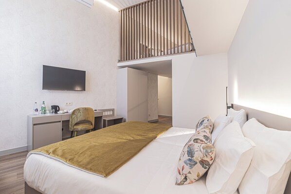 A modern hotel room with a bed, a desk, a chair, a TV, and a staircase. - Galega Villas (Mafra)